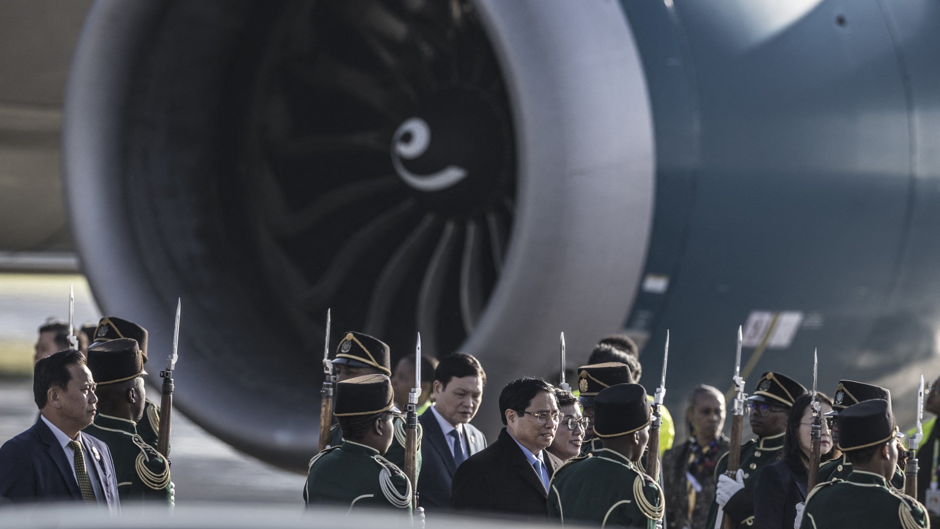 Vietnam Prime Minister Pham Minh Chinh (C) walks through a South African National Defense Forces (SANDF) honor guard upon his arrival at the OR Tambo International airport in Ekurhuleni on November 21, 2025 ahead of the G20 leader's Summit.