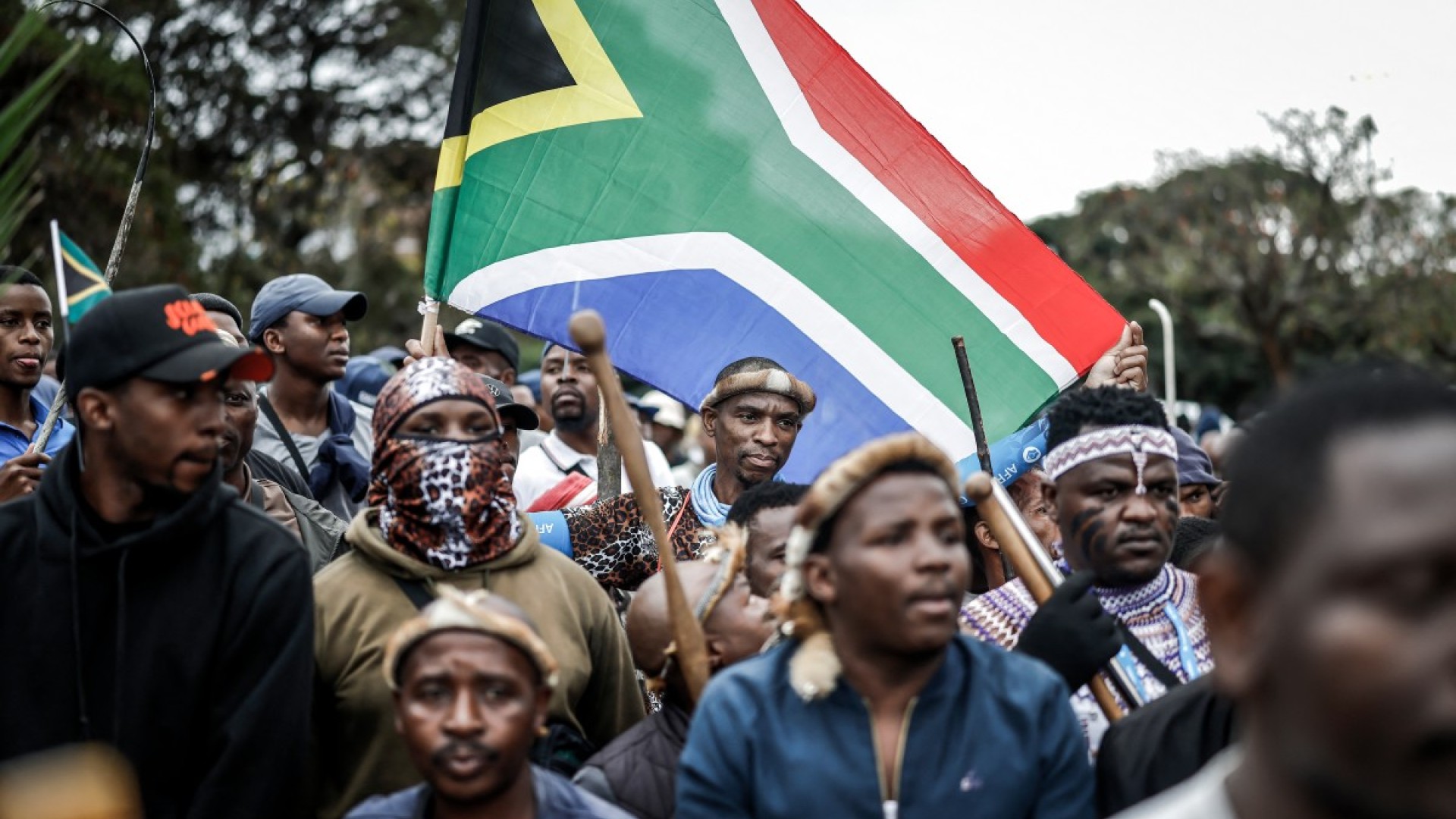 Members of the Zulu regiment known as the ‘Amabutho’ hold a South African flag as they march during a demonstration by the "March and March" movement. AFP/Marco Longari