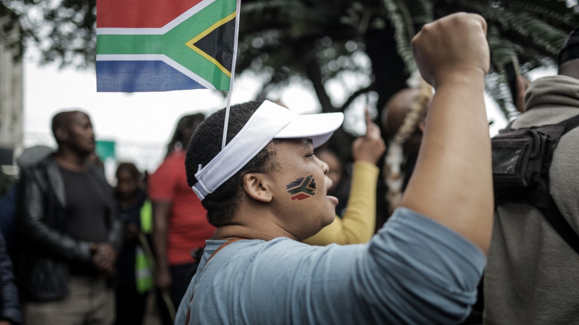 A protester gestures while wearing a South African flag over her head during a demonstration by the "March and March" movement. AFP/Rajesh Jantilal