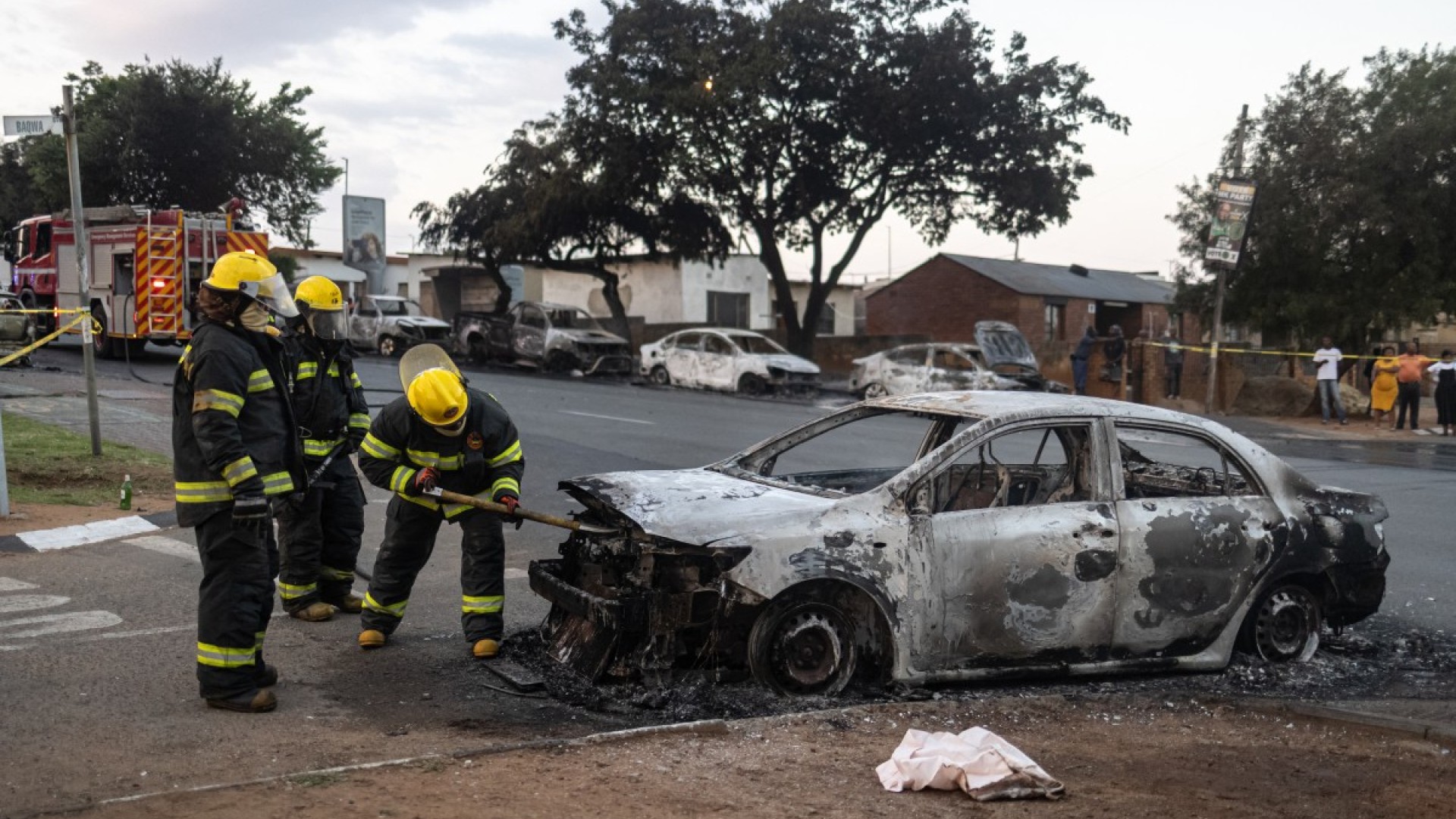 Firefighters spray water into a burning vehicle following clashes between local residents and foreign nationals in Soweto on October 8, 2026.