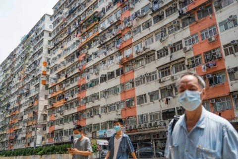 Pedestrians cross a road past apartment blocks in Hong Kong's To Kwa Wan area during intense heat