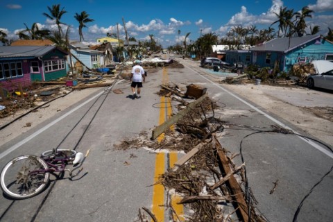 A man walks pass debris scattered on Pine Island Road in the aftermath of Hurricane Ian in Matlacha, Florida 