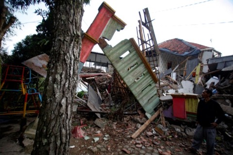 A man stands beside damaged houses following the earthquake in Cianjur on November 21, 2022