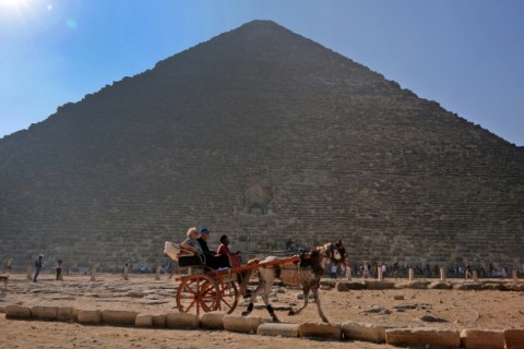 The Giza pyramids remain popular for more traditional tourism too: here people ride in a horse-drawn cart past the ancient Egyptian king Khufu's Great Pyramid 