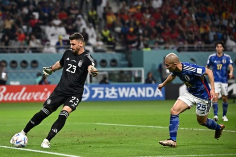 Spain goalkeeper Unai Simon (L) clears the ball ahead of Japan forward Daizen Maeda