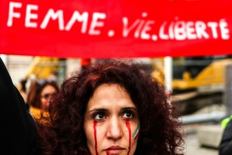 A protestor with red tears painted on her face during a rally in support of the demonstrations in Iran, in Toulouse, south-western France, on December 3