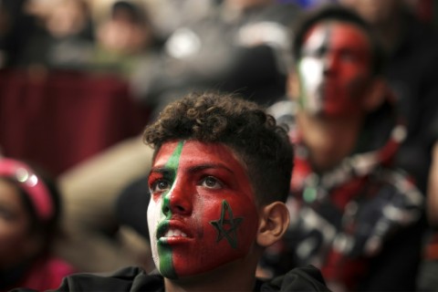 Palestinian football fans with faces painted in the colours of the national and Moroccan flags watch the Qatar 2022 World Cup on December 10