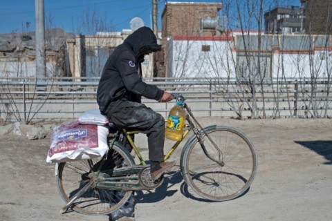 An Afghan man with his bicycle stacked with food aid rides through Kabul, where aid groups say they have been pushed to the wall by a Taliban ban on women working with NGOs