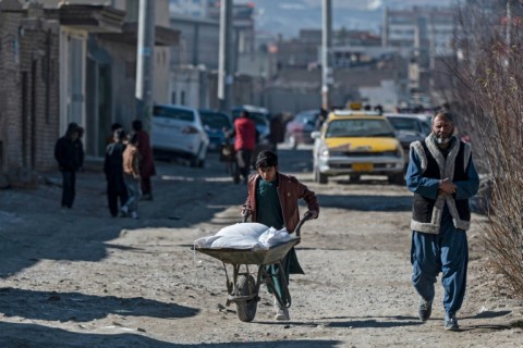 An Afghan boy pushes a wheelbarrow loaded with food aid through Kabul, where aid groups say they have been pushed to the wall by a Taliban ban on women working for NGOs