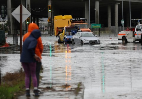 A tow truck pulls a car out of a flooded intersection on January 4, 2023 in Mill Valley, California
