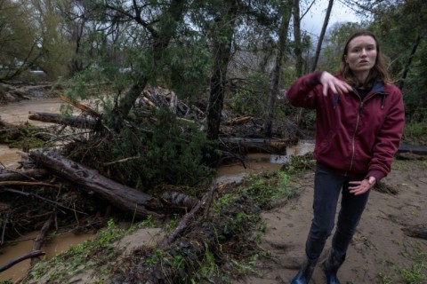 Amberlee Galvin stands next to evidence of the flooding that has ravaged the town of Felton 