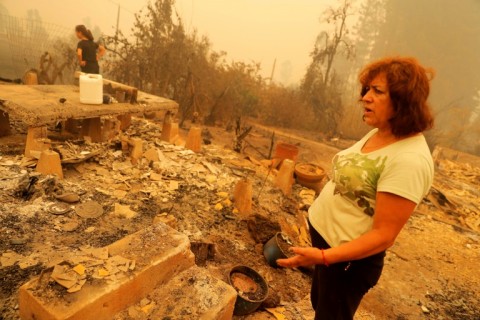 A woman observes ruins left by a fire that has left at least 24 people dead in Chile
