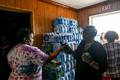 A volunteer carries jugs of water and supplies from a makeshift clinic and relief center in Rolling Fork, Mississippi