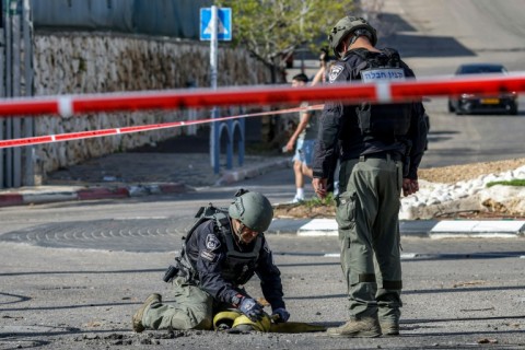 An Israeli police bomb disposal unit member inspects the remains of a rocket fired from Lebanon and intercepted by Israel in its northern town of Shlomi 