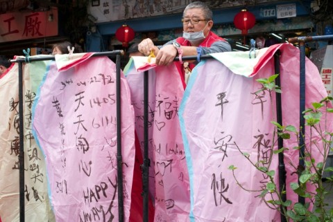 A vendor hangs sky lanterns with messages of peace written on them at the Shihfeng train station in New Taipei City 