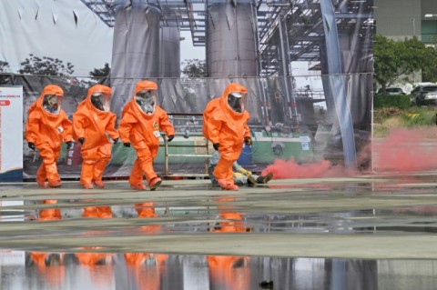 Rescuers in protective equipments walk past a mock collapsed nuclear power plant during a civilian drill while imitating a Chinese attack in Taichung in April 2023
