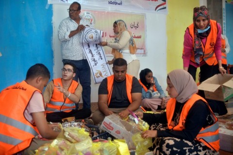 Egyptian volunteers prepare aid packages for refugees fleeing fighting in Sudan