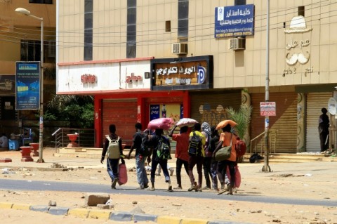 People carrying their belongings walk along a street in Khartoum as fighting rages on