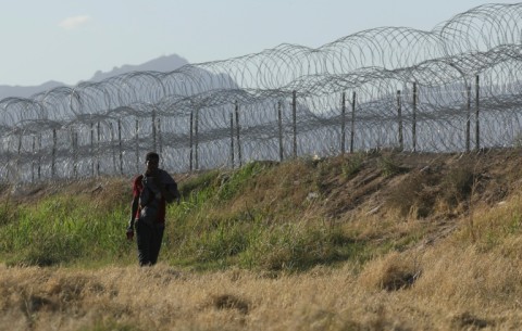 A migrant walks along the banks of the Rio Grande river to surrender to US border agents from El Paso, Texas