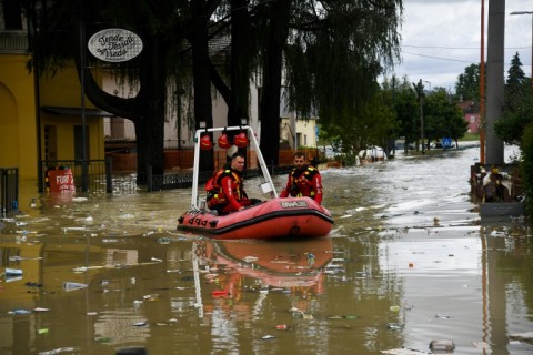 Volunteer firefighters ride their dinghy across a street flooded by the river Savio in the Ponte Vecchio district of Cesena, central eastern Italy, on May 17, 2023