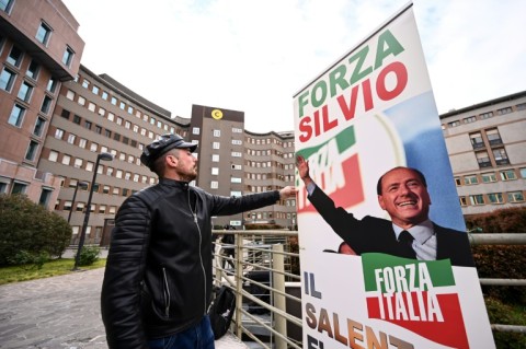 A man sets up a banner reading "Go Silvio!" in front of San Raffaele hospital 