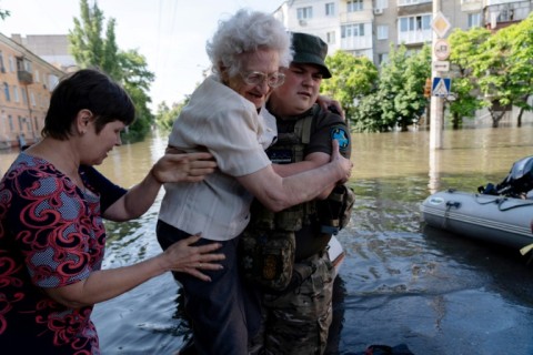 A Ukrainian serviceman helps local residents during an evacuation from a flooded area in Kherson