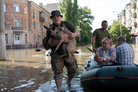 Ukrainian servicemen help local residents during an evacuation from a flooded area in Kherson
