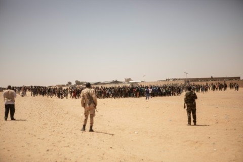 Niger Armed Forces soldiers watch a crowd of migrants gathering in Assamaka, near the border with Algeria