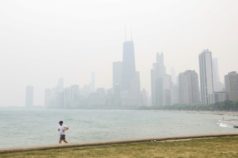 A jogger runs along the shoreline of Lake Michigan with heavy smoke from the Canadian wildfires covering the city of Chicago in a thick haze
