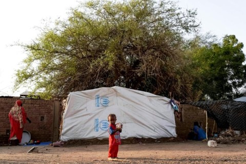 A displaced child outside a tent in al-Hasaheisa, where some of the more than 2.4 million people uprooted by Sudan's war have fled