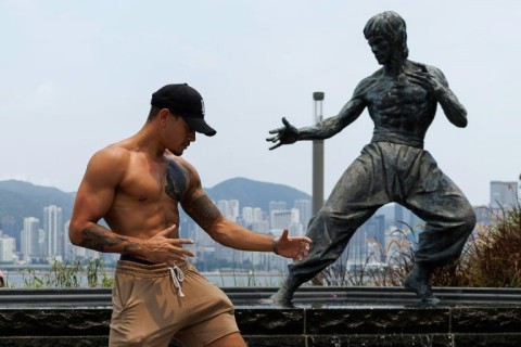 A visitor poses with a statue of Bruce Lee on Hong Kong's waterfront promenade