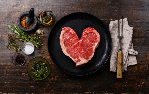 Heart-shaped steak in a frying pan. GettyImages/Lisovskaya