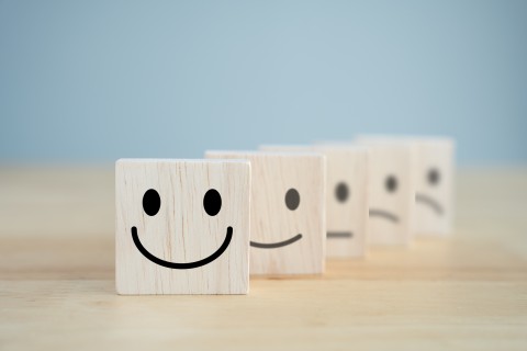 Wooden blocks representing happiness and sadness. GettyImages/Wipada Wipawin
