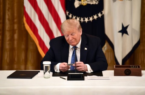 Former US president Donald Trump, holding a debit card during a 2020 cabinet meeting, has broad dicretion to spend campaign funds on legal bills