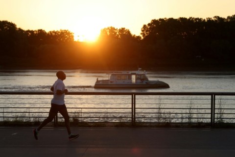 A man jogs along the docks at sunrise to avoid the heat, in Bordeaux, southwestern France