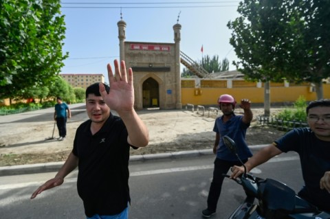 This picture taken on July 18, 2023, shows local people trying to prevent the taking of a photo outside a mosque in Azatbagh village, outside Yarkant in Xinjiang