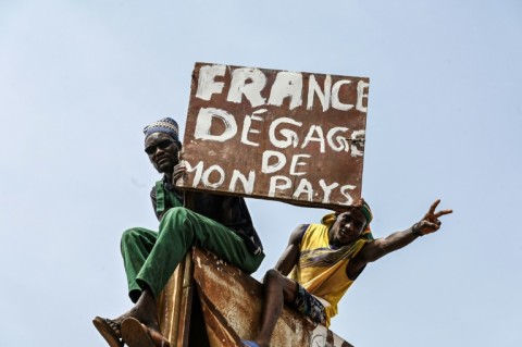 A man burns holds a placard reading 'France get out of my country' 