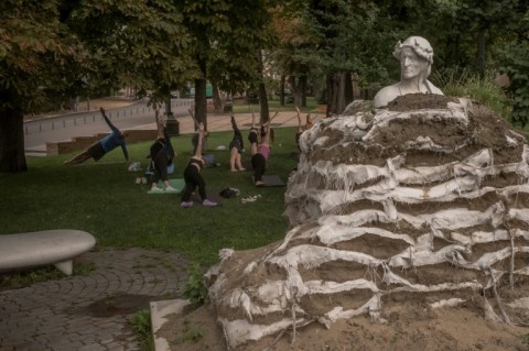 People exercise next to a monument to Italian poet Dante Alighieri, wrapped in sandbags to prevent it from damage from Russian air attacks, in Kyiv