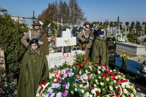 Soldiers stand guard as people lay wreaths  during a ceremony at the grave of The Ulma family