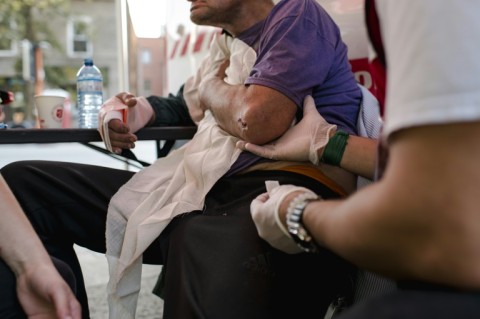 Aydin, director of emergency services and disaster assistance, offers a comforting hand to an injured homeless man as Bettina, a nurse, treats and checks his health in Montreal