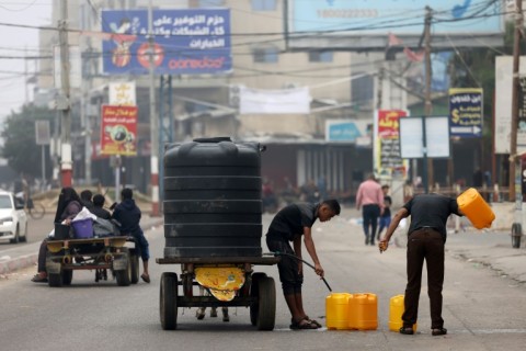 Men fill plastic jerricans with scarce srinking water in Rafah in the southern Gaza Strip on October 23, 2023