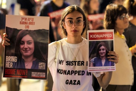 A woman holds placards showing one of the Israeli hostages, Karina Ariev, held by Palestinian militants since the October 7 attack