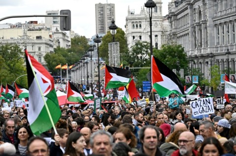 Protestors wave Palestinian flags and hold signs at a demonstration in support of the Palestinian people in Madrid