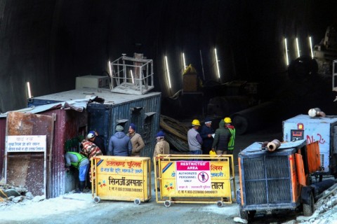 Police and officials stand at the entrance of the road tunnel that collapsed in India's Uttarakhand state