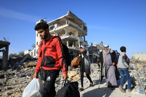 On the first day of a four-day truce, Palestinians walk through debris upon their return to Khan Yunis, in southern Gaza, to inspect their homes following weeks of Israeli bombardment