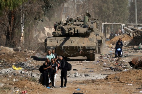 Palestinians pass an Israeli tank as they flee the north of Gaza