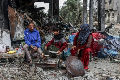 Palestinians cook outside amid the ruins of homes near Abasan in the southern Gaza Strip