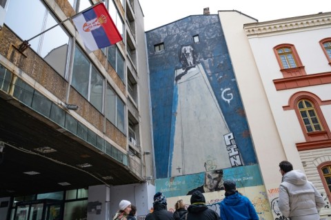 Tourists gather in front of a mural to assassinated Serbian prime minister Zoran Dindic