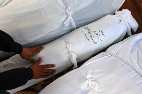 A man mourns at Al-Najjar hospital beside the shrouded bodies of relatives killed in Israeli bombing of Rafah in the southern Gaza Strip