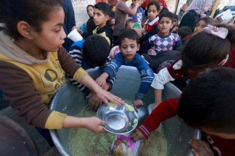 Palestinian children collect food at a donation point provided by a charity group in the southern Gaza city of Rafah